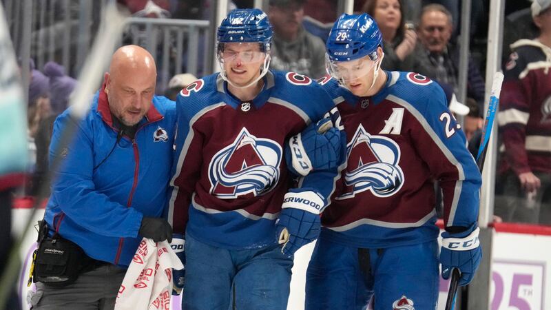 Colorado Avalanche left wing Artturi Lehkonen, center, is helped to the team box by trainer...