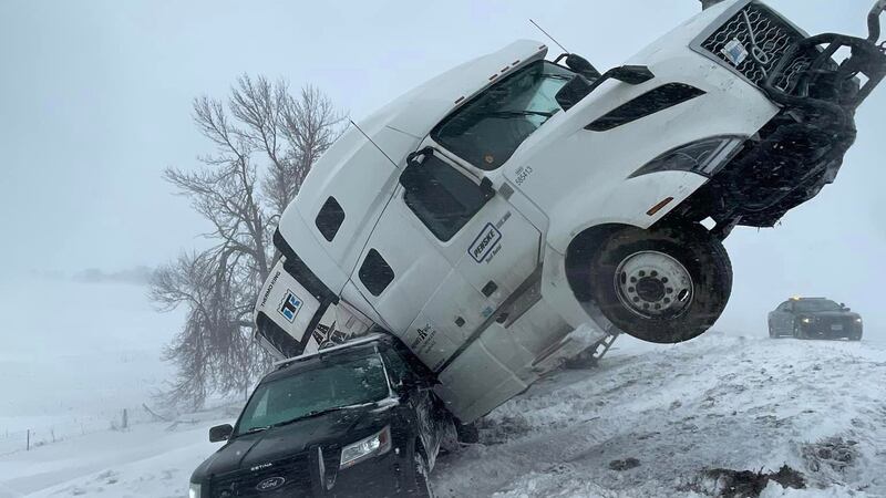 A semi rests precariously against a South Dakota Highway Patrol cruiser on Interstate 90.